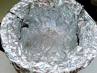 4、坤博砂锅烤紫薯,另一张锡纸也放入锅内，十字交叠成直简状，一圈贴牢砂锅内壁，顶部包住砂锅边沿。