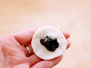 10、萌猪黑芝麻汤圆,取一块醒发好的白色面团、按成饼状后包入黑芝麻馅料