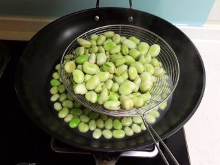 3、蚕豆火腿肠炒饭,把焯好的蚕豆捞出来，晾至不烫手，给蚕豆剥皮