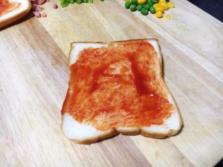 6、鲜虾吐司披萨,将适量的番茄酱涂抹在吐司片上。