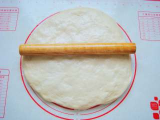 15、葡萄干司康,放在垫子上按扁,开始擀成片。