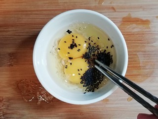 2、青椒虾皮鸡蛋卷,将鸡蛋打入碗中,倒入虾皮和黑芝麻。