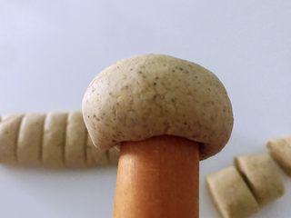 5、黑豆渣窝窝头,面团放左手掌心，用手不好弄就用擀面杖摁出小窝，慢慢摁一圈。