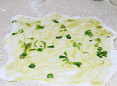 5、千层肉酥饼,面团分两等份。取一份擀成薄皮，尽可能能地薄。用一半的青葱和葱油抹在上面。再在面皮左右两边上下各1/3处往里切上一刀，切开的每一刀的位置大概是面皮横着的1/3