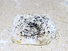 12、千层肉酥饼,翻面过来，把四周大概封一下，撒点黑芝麻，稍微再往下压一下，压薄一些。同样的操作，将剩下的一半面团也如是操作