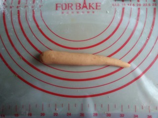 6、象形胡萝卜馒头,分成每个40-45克左右的小面团，将面团搓长一点，一边大一边小，搓出胡萝卜的外形。