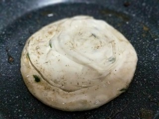 14、烫面椒盐葱花酥饼,不粘锅中加入食用油。将饼胚放入锅中。