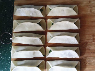 8、磷虾韭菜锅贴,将上、下两边向中间对折捏紧既可,包好后放至案板上