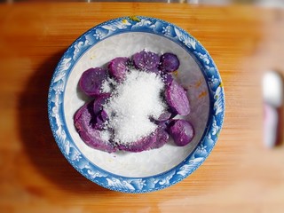 5、紫薯南瓜糯米糕,将蒸熟的紫薯去皮，并倒入白砂糖。