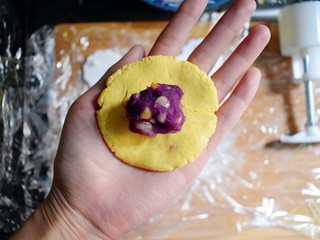 21、紫薯南瓜糯米糕,取一个面剂子，用手压成圆形，放一个紫薯花生丸。
