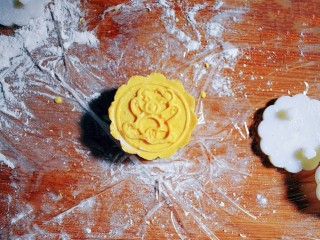 24、紫薯南瓜糯米糕,取月饼模具，按压出花形。（我的月饼模具是50g的，所以面团约30g，里面包的紫薯花生丸约20g，大家可以根据自己模具的大小来分剂子。）月饼模具上要抹点油哦，防黏。