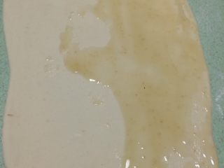 9、早餐美味鸡蛋灌饼,取一个剂子揉几下后擀成牛舌状，尽量擀薄一点，之后把油酥糊抹在面饼一半