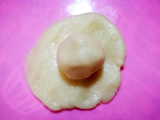 5、简易版老婆饼,开始包油酥了，取一个油皮压扁，包入油酥，像包包子一样，一定把口捏紧。