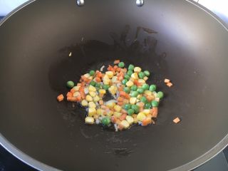 6、芝士焗番茄鲜虾米饭盅,首先放入胡萝卜和豌豆，炒30秒左右。