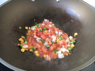 8、芝士焗番茄鲜虾米饭盅,放入番茄粒翻炒均匀。