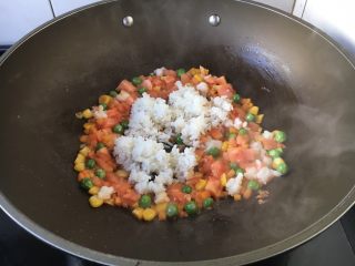 9、芝士焗番茄鲜虾米饭盅,放入米饭，将米饭炒散，翻炒均匀。
