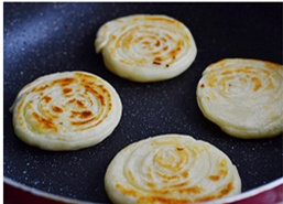 17、油旋,烤好的饼拿在手中，用拇指在饼的中间按一下，让饼的层次出来即可。