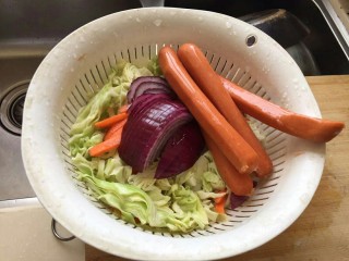 1、卷心菜香肠炒面,准备好材料，半根胡萝卜，1/4的卷心菜，半个洋葱，四五根香肠。