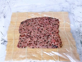 12、血糯米粢饭团,将席卷上铺上一张保鲜膜，放上血糯米，压平整。