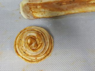 14、油旋儿,14．用左手大拇指和食指捏住饼胚的一头，另一只手绕圈圈，将其全部绕住，尾部藏在底下压住。