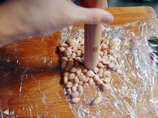 10、紫薯南瓜糯米糕,将晾干的花生米用保鲜膜包起来，并用擀面杖捣碎，去除比较容易去的花生皮（也可不去）。