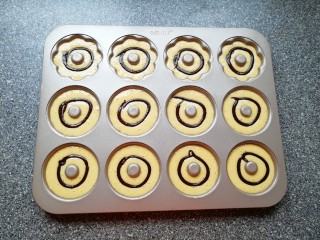 9、双色甜甜圈,再挤入原味蛋糊，八分满即可，最后用可可蛋糊装饰。