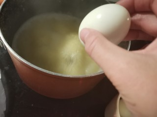 6、鸡蛋小米粥,煮沸的锅中放入鸡蛋。