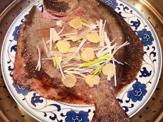 6、清蒸多宝鱼,多宝鱼摆入盘中上面再摆一些葱姜放入蒸锅大火蒸15分钟