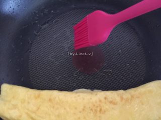 9、爱心玉子烧,卷后的鸡蛋卷靠边，在锅上再刷上一层薄薄的食用油，也可不刷。倒入1/3鸡蛋液继续煎至差不多溶固时卷起成卷