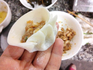 14、鲜肉小笼包,然后取一张饺子皮,放上适量肉馅。捏出褶皱,如图中的样子。