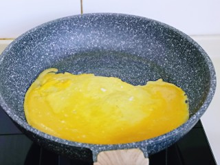 6、小熊便当套餐,起锅，不粘锅刷上一层薄薄的食用油，再倒入打散的蛋液，小火剪至表面蛋液凝固即可关火。