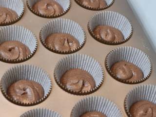 13、巧克力熔岩杯子蛋糕,	将面糊装入裱花袋中。先在杯子蛋糕纸托中挤一层面糊