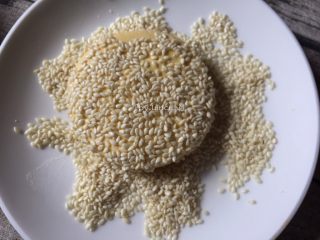 11、芝麻南瓜饼,放到装了白芝麻的盘中，使面饼两面均匀地粘上芝麻