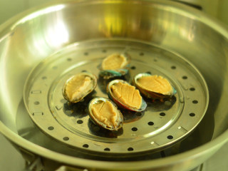 7、蚝汁鲍鱼,将处理好的鲍鱼肉放入鲍鱼壳里,摆上蒸锅,大火蒸8-10分钟左右