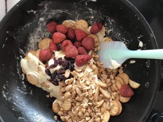 7、网红草莓雪花酥,在把草莓干，蔓越莓干和花生碎倒入锅中，快速搅拌然后关火