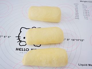8、绵绵吐司,依次把所有的面团用擀面杖擀成牛舌状再卷起来,盖保鲜膜松弛15分钟