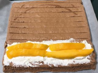 19、芒果蛋糕卷,蛋糕有余热的时候,均匀的涂抹奶油霜,再放入芒果条。