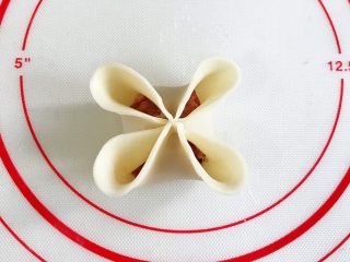 12、四喜蒸饺,先给饺子皮对角刷点水，筷子对角夹紧，再把每一个花瓣边缘捏薄些。