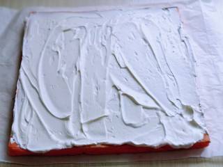 18、红丝绒草莓奶油蛋糕卷～下午茶必备甜品,将蛋糕片放一张油纸上面，打发的奶油涂抹在蛋糕片上。借助擀面杖和油纸从一段卷起来即可，放入冰箱冷藏1小时以上再切开。(奶油留一些，做装饰用)