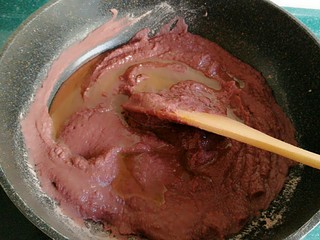 6、自制红豆沙馅,把中火调到小火，加入二分之一的玉米油，加了玉米油的豆沙变的比之前稀了一些。