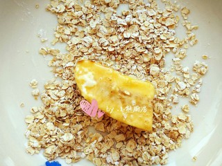 6、燕麦脆皮香蕉卷,裹满蛋液后就很容易粘上燕麦片了，让香蕉在燕麦片中翻滚一圈之后，可以再用手捏起燕麦片撒在上面，这样燕麦包裹的更多更均匀