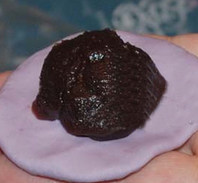 7、紫薯糯米团,取一个面团压扁，中间稍厚一点，四边压薄一点，中间放20克豆沙馅，包好后收口朝下放在硅油纸上。