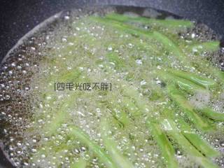 7、干煸四季豆,起锅烧热油,以高火高温将四季豆炸制表皮起皱捞出;