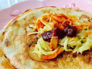 16、快手版老北京春饼（土豆丝卷饼）,取一张薄饼，加适量土豆丝，也可以再加些小咸菜，最后放一小勺黄豆酱