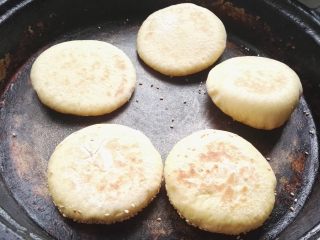 16、芝麻玉米面白糖饼,勤转圈，再次翻面，用手按下能迅速弹起就熟了，取出放筐中，用布盖着（利用余温蒸汽再焖焖）。