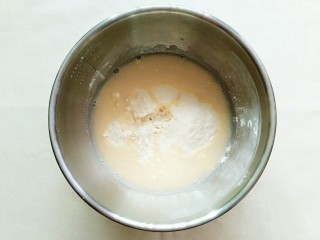 6、紫薯玉米千层糕,倒一半的牛奶白糖液至300g的玉米面粉里！用勺子搅拌一下！