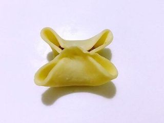 6、四喜饺子，让生活喜气洋洋,再将另两边的面皮也往中间对折中间点捏在一起，就会出现四个孔。