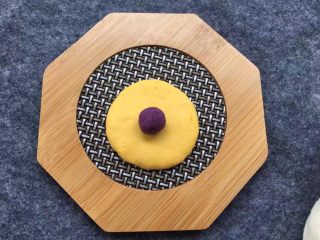 12、紫薯南瓜椰蓉球,取一小块南瓜面团压扁，放上紫薯馅，南瓜面团由外向内慢慢收口，把紫薯面团包裹在里面，再搓成圆球。