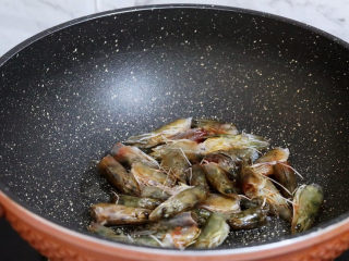 4、潮汕海鲜粥,锅中倒入适量的食用油烧热,放入虾头