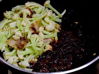 7、干锅菜花,菜花刚刚开始变色时，把它推到锅子一边，放入豆瓣酱小火炒出红油。利用锅底的余油就好，不必另外放油。
